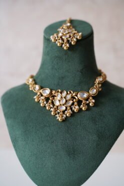 Small delicate floral kundan gold necklace set with jhumka earrings and matching tikka in traditional Indian design