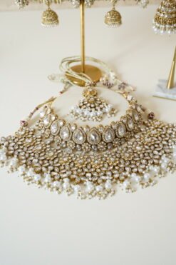 Two-layer Indian Pakistani bridal necklace set with clear stones and pearls featuring matching earrings and tikka, adjustable drawstring design for versatile styling