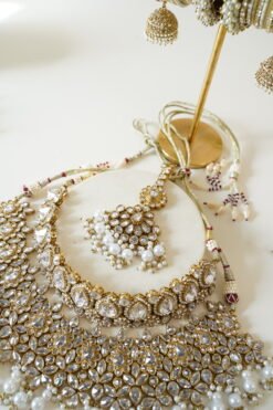 Two-layer Indian Pakistani bridal necklace set with clear stones and pearls featuring matching earrings and tikka, adjustable drawstring design for versatile styling