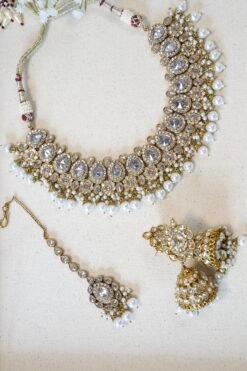 Clear stone necklace set with pearl detailing featuring matching jhumka earrings and tikka in traditional desig