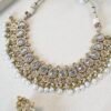 Clear stone necklace set with pearl detailing featuring matching jhumka earrings and tikka in traditional desig