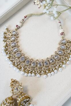 Clear stone necklace set with pearl detailing featuring matching jhumka earrings and tikka in traditional desig