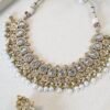 Clear stone necklace set with pearl detailing featuring matching jhumka earrings and tikka in traditional desig