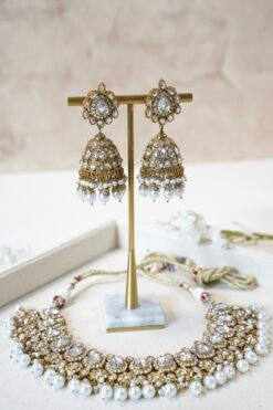 Clear stone necklace set with pearl detailing featuring matching jhumka earrings and tikka in traditional desig