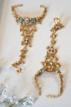 Bridal haathphool (Indian hand harness) in an intricate gold-tone design featuring a central floral motif connected by delicate chains to a statement ring, elegantly draping across the hand for a traditional wedding look