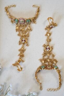 Bridal haathphool (Indian hand harness) in an intricate gold-tone design featuring a central floral motif connected by delicate chains to a statement ring, elegantly draping across the hand for a traditional wedding look
