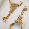 Bridal haathphool (Indian hand harness) in an intricate gold-tone design featuring a central floral motif connected by delicate chains to a statement ring, elegantly draping across the hand for a traditional wedding look