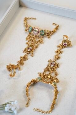 Bridal haathphool (Indian hand harness) in an intricate gold-tone design featuring a central floral motif connected by delicate chains to a statement ring, elegantly draping across the hand for a traditional wedding look