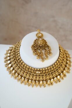 raditional gold finish kundan necklace set with matching earrings and maang tikka, featuring intricate detailing and a bold statement design