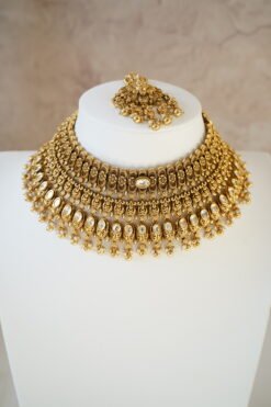 raditional gold finish kundan necklace set with matching earrings and maang tikka, featuring intricate detailing and a bold statement design