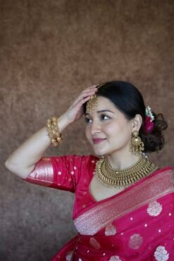 Bride wearing a traditional gold finish kundan necklace set with matching earrings and maang tikka, featuring intricate detailing and a bold statement design
