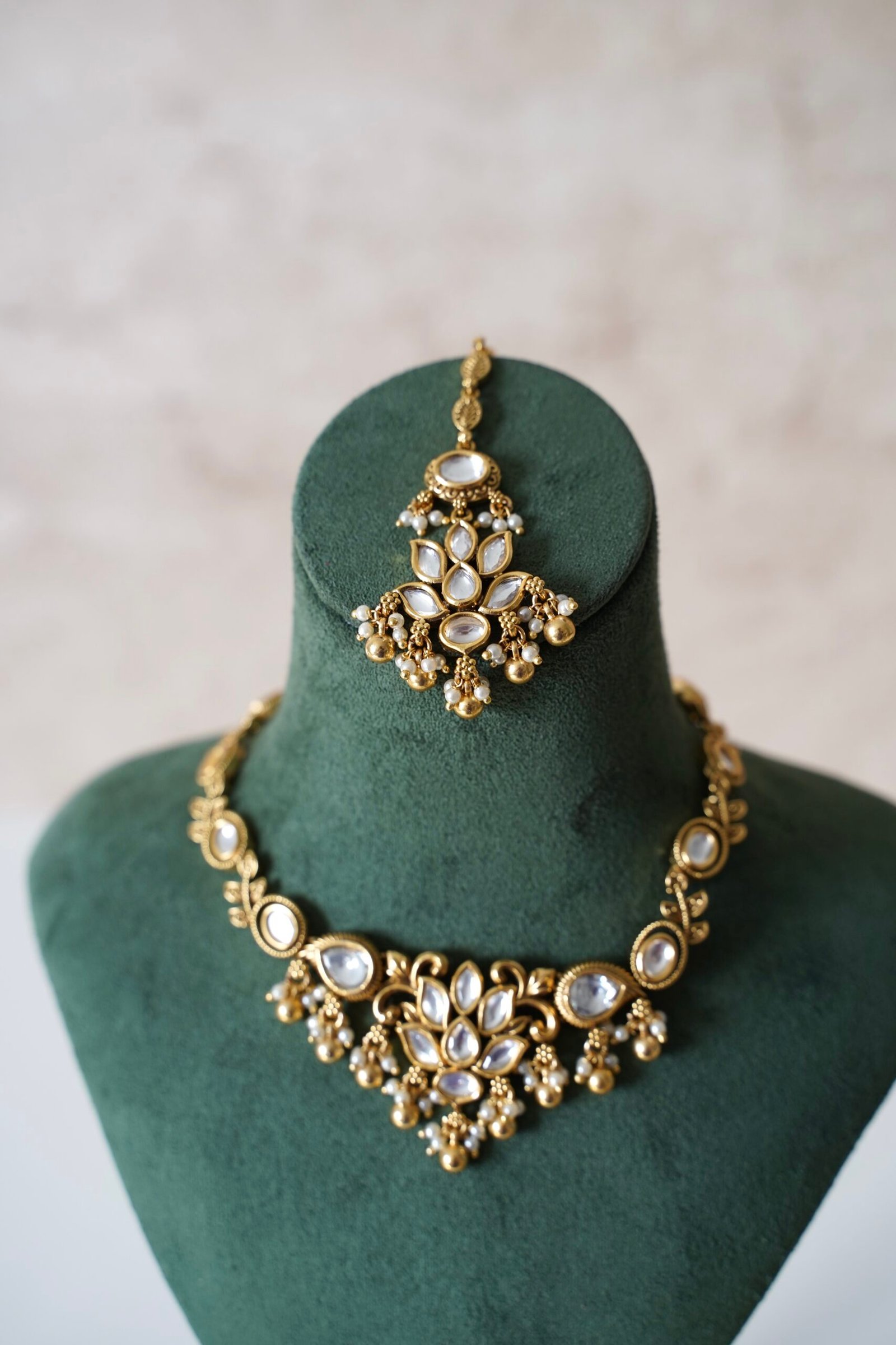 Small delicate floral kundan gold necklace set with jhumka earrings and matching tikka in traditional Indian design
