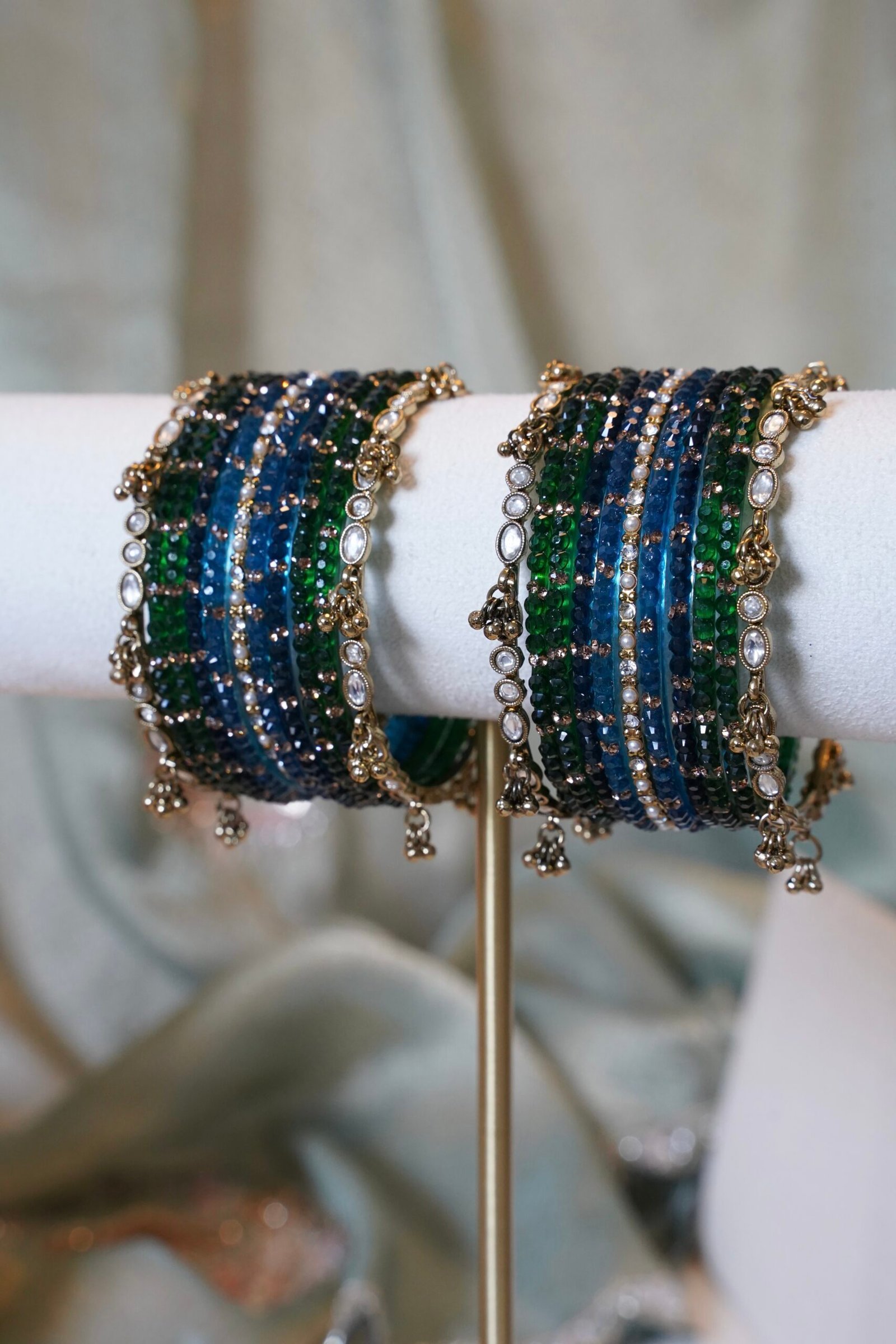 Deep blue and green Kashmiri glass bangle set inspired by peacock colors, featuring layered tones and a delicate ghungroo bangle at the edge of the stack
