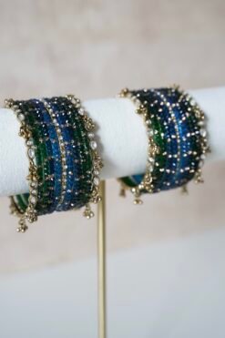 Deep blue and green Kashmiri glass bangle set inspired by peacock colors, featuring layered tones and a delicate ghungroo bangle at the edge of the stack