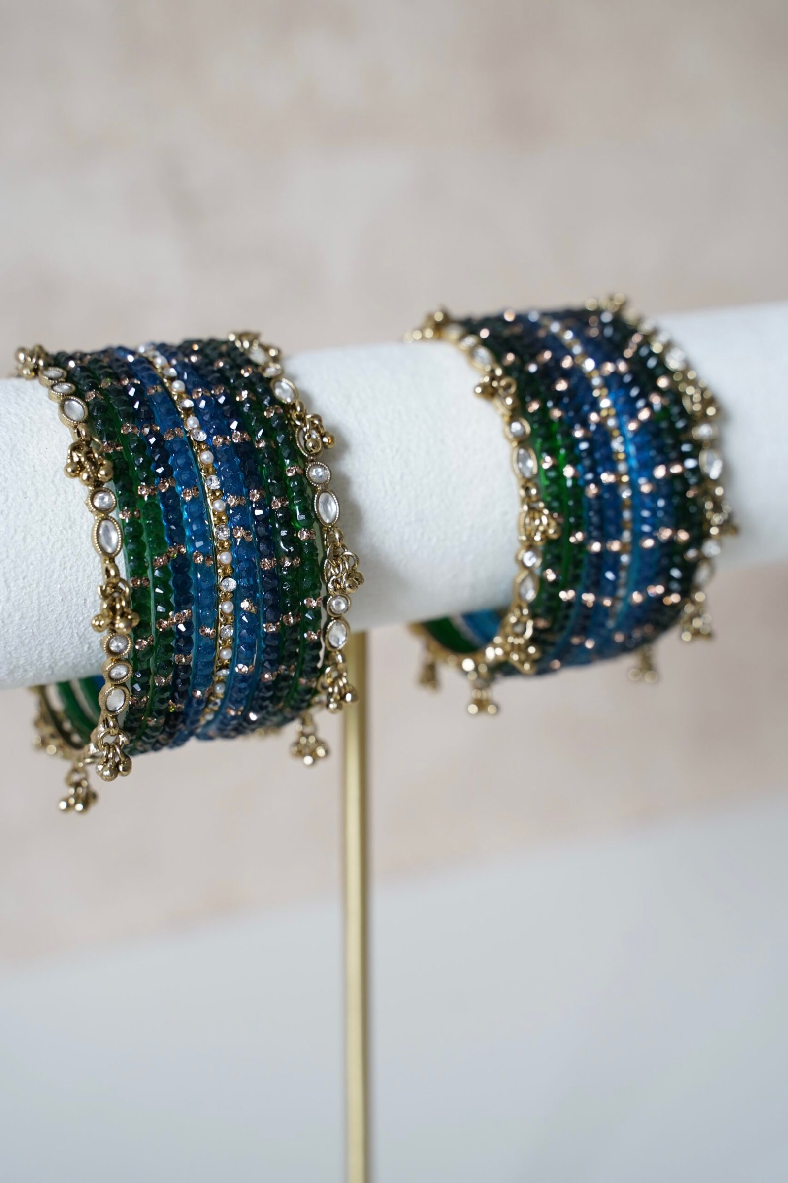 Deep blue and green Kashmiri glass bangle set inspired by peacock colors, featuring layered tones and a delicate ghungroo bangle at the edge of the stack