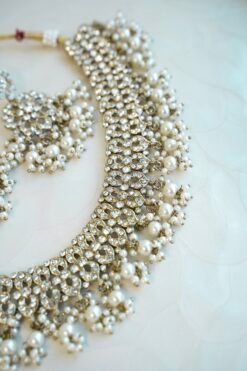 Sparkly flexible zircon necklace featuring flower shaped flower petal drop earrings and a matching pearl-beaded tikka.