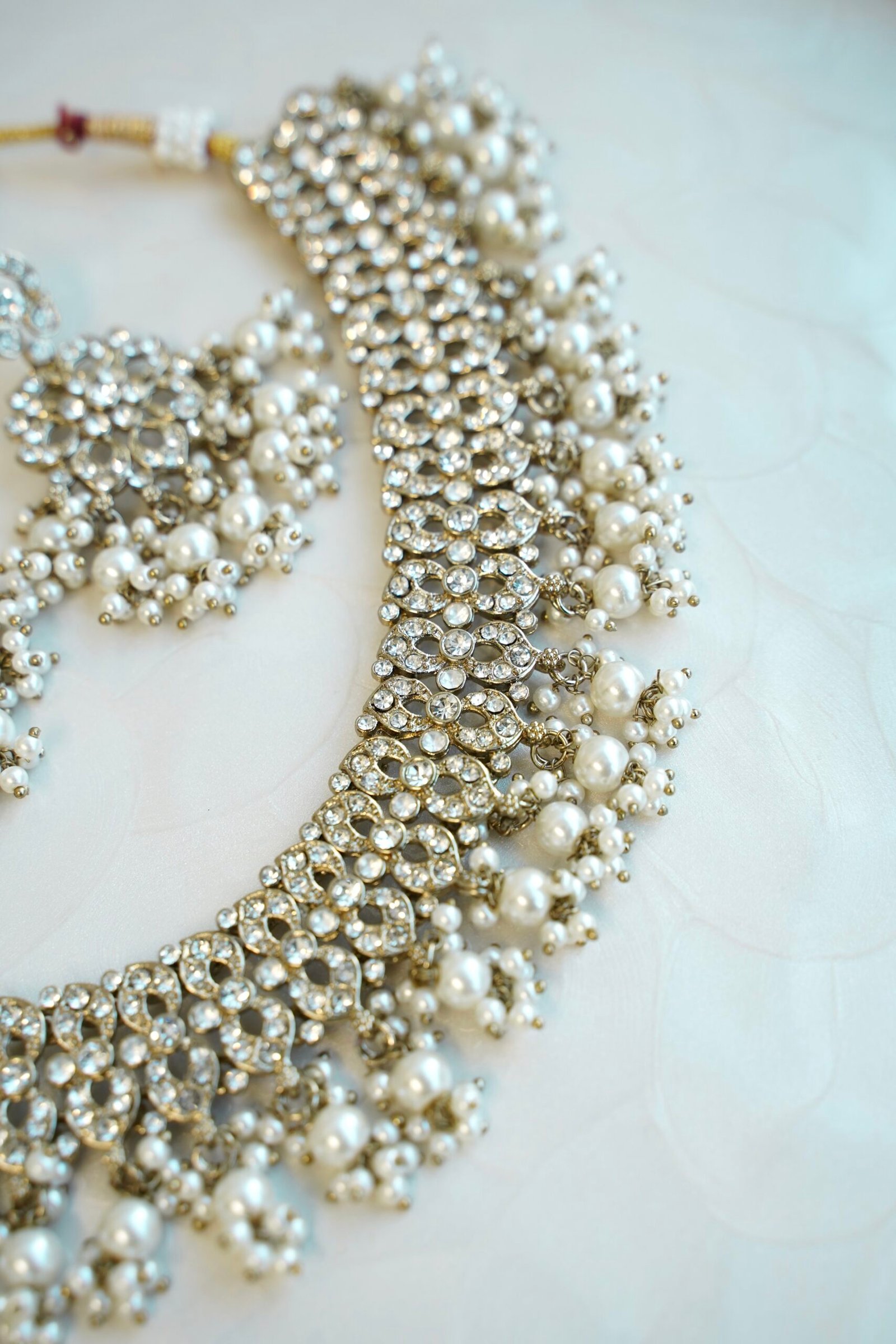 Sparkly flexible zircon necklace featuring flower shaped flower petal drop earrings and a matching pearl-beaded tikka.
