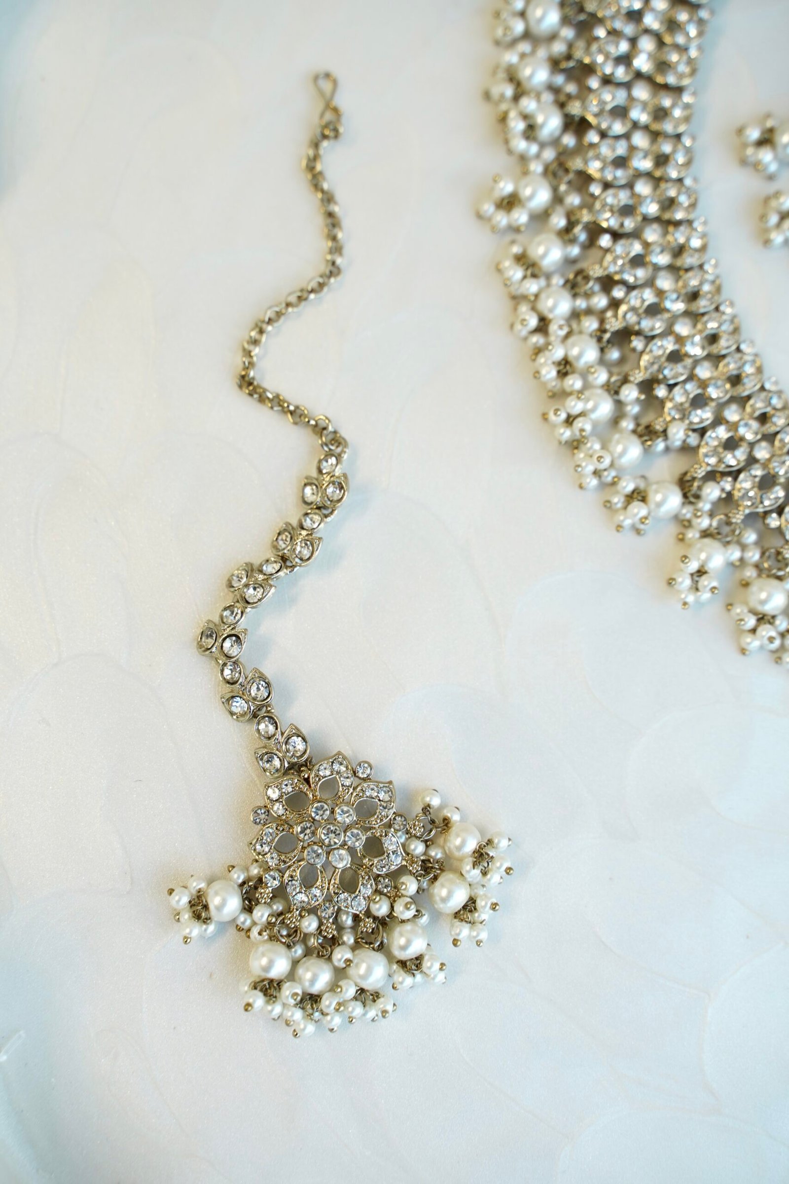 Sparkly flexible zircon necklace featuring flower shaped flower petal drop earrings and a matching pearl-beaded tikka.