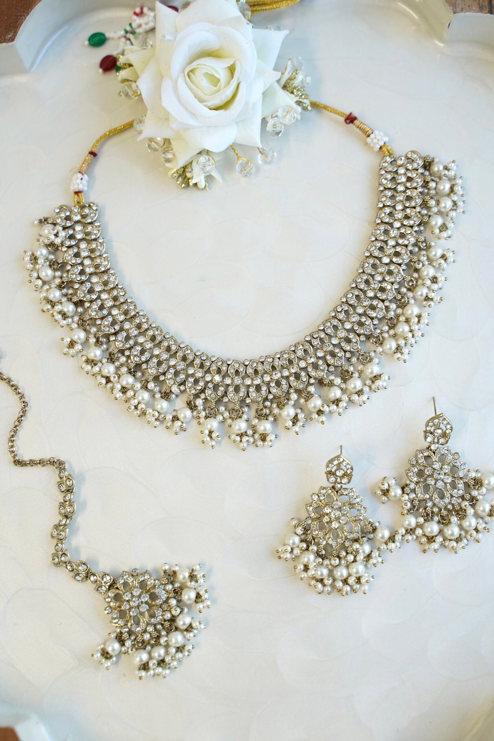 Sparkly flexible zircon necklace featuring flower shaped flower petal drop earrings and a matching pearl-beaded tikka.