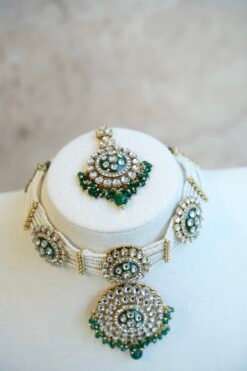 Green artificial Kundan choker necklace featuring a drop pendant and pearl beads, complete with matching earrings and tikka.