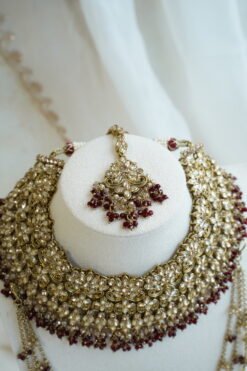 Seyora Jewels bridal jewelry set featuring a champagne stone necklace with maroon beads, matching jhumka earrings with kanchain, maang tikka, and passa.
